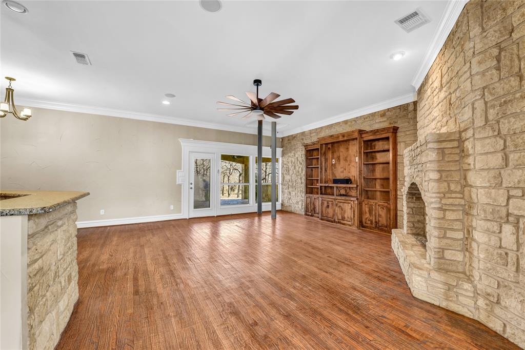 116 McClintock Court Weatherford, TX 76088 - Photo 37 of 38 Lining room wood finished floors, fireplace, ceiling fan, and hanging lights