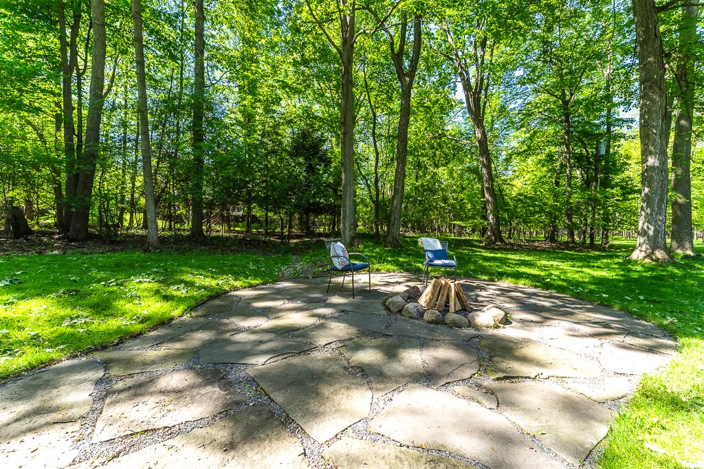 220 Hibiscus Drive Rochester, NY 14618 - Photo 17 of 50 A delightful firepit, with a wooded thicket as backdrop, is a charming outdoor gathering spot.