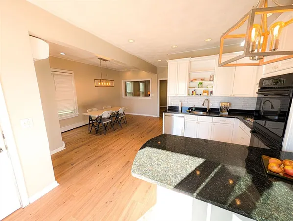 a living room with stainless steel appliances furniture a rug and a kitchen view