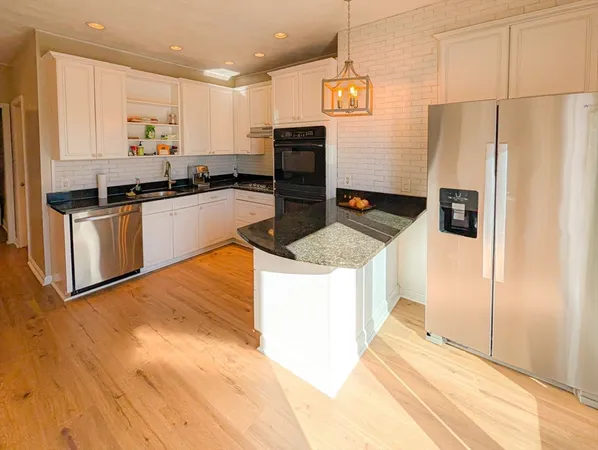 a kitchen with stainless steel appliances granite countertop a refrigerator a stove and a sink with wooden floor
