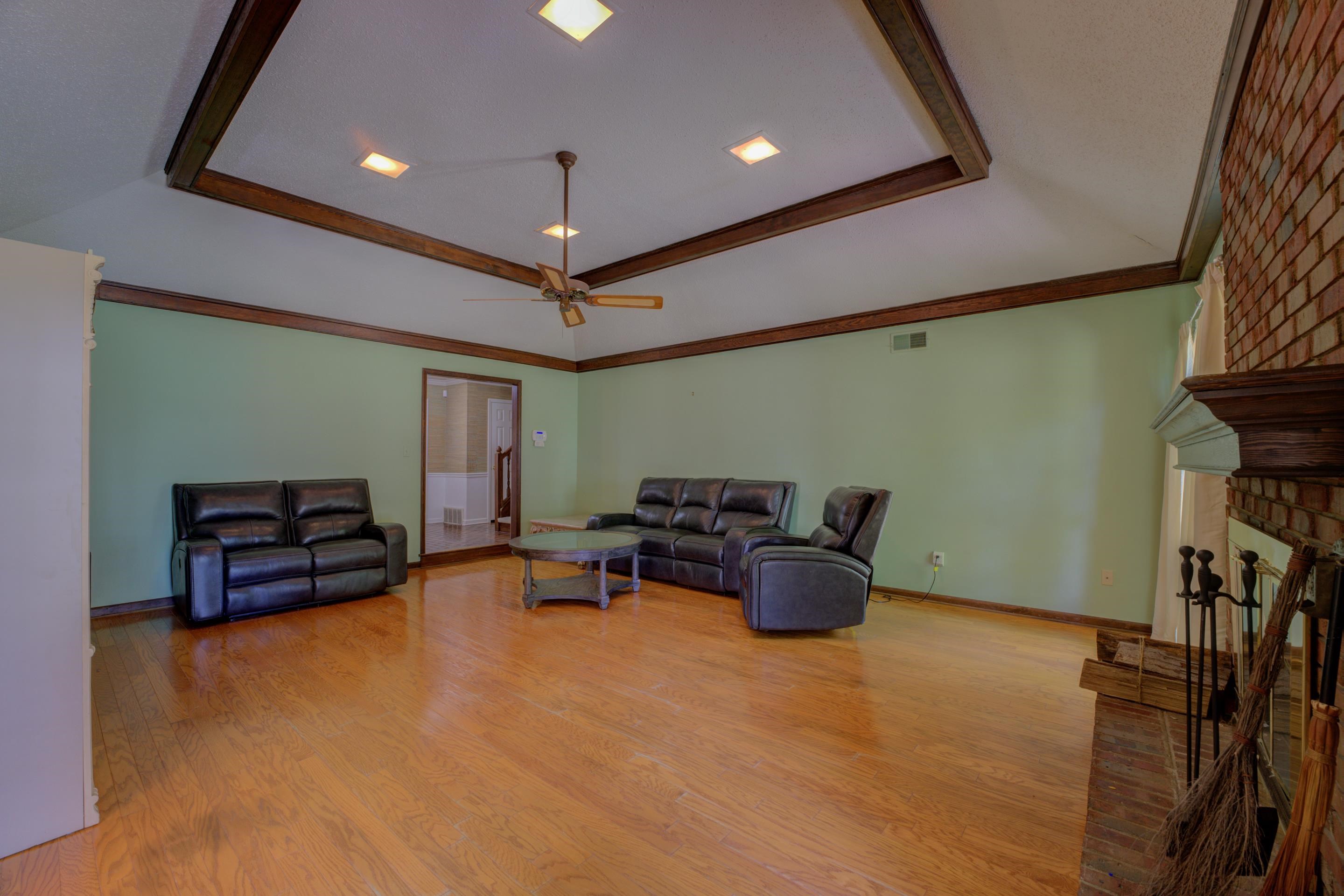 2031 Corbin Road Germantown, TN 38139 - Photo 3 of 27 Living room featuring light wood-type flooring, brick wall, ceiling fan, and a fireplace