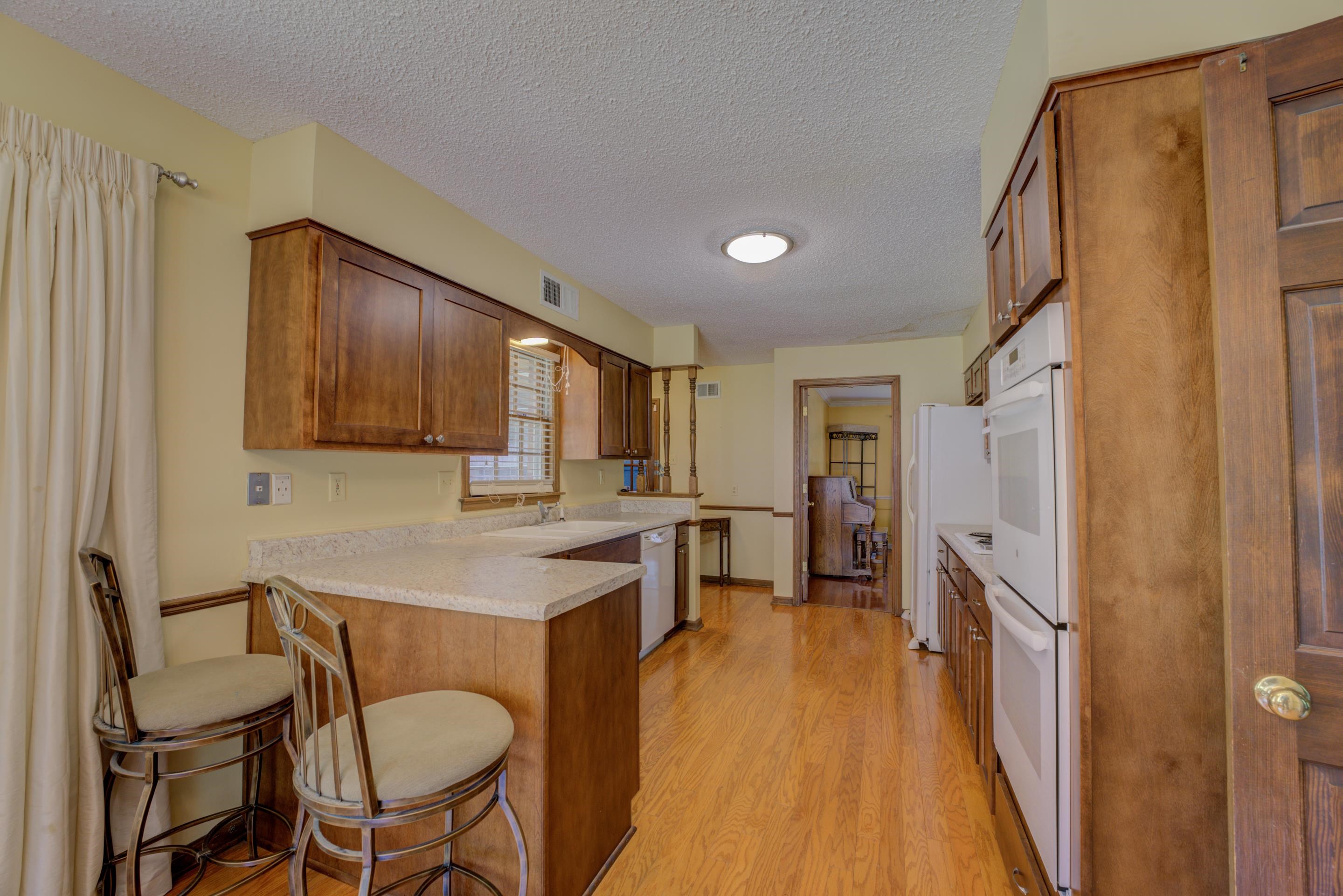 2031 Corbin Road Germantown, TN 38139 - Photo 6 of 27 Kitchen featuring light wood-type flooring, a textured ceiling, a kitchen bar, and white dishwasher
