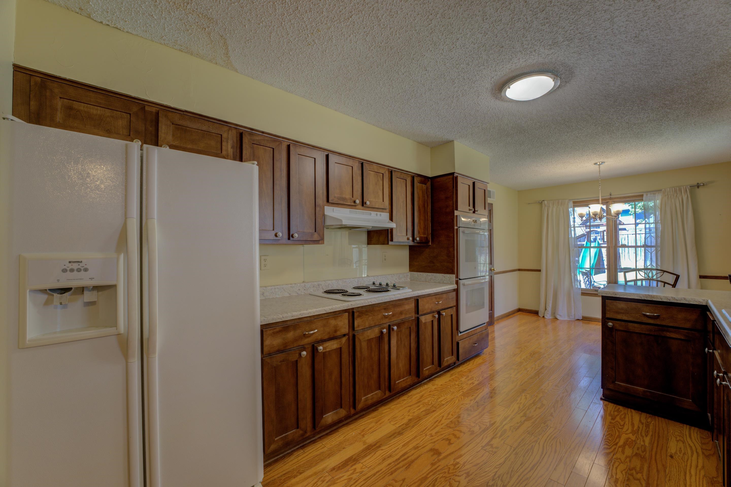 2031 Corbin Road Germantown, TN 38139 - Photo 7 of 27 Kitchen with a notable chandelier, white appliances, light hardwood / wood-style floors, a textured ceiling, and pendant lighting