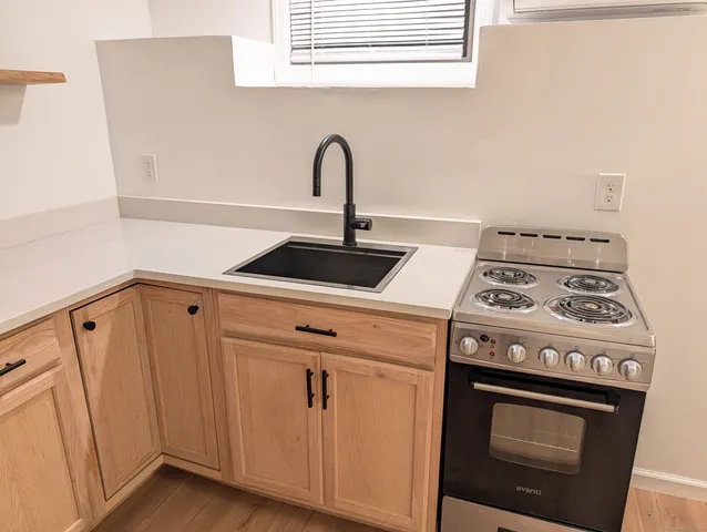 a close view of a stove and white cabinet with a sink
