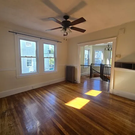 a view of an empty room with window and wooden floor