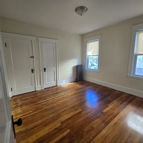 a view of empty room with window and wooden floor