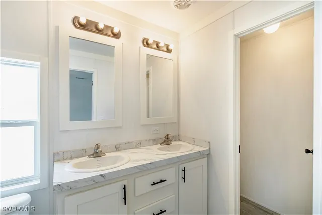 a bathroom with a granite countertop sink mirror and a toilet