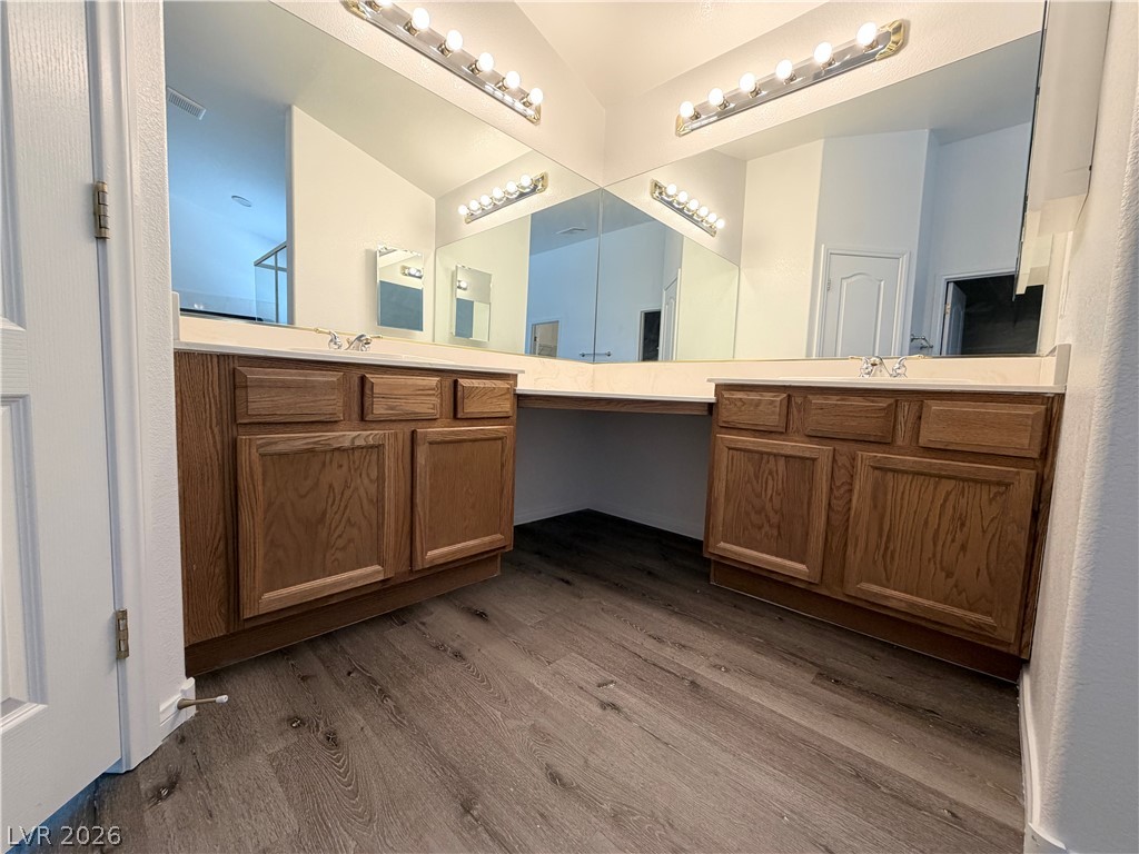 6116 Rabbit Track Street Las Vegas, NV 89130 - Photo 12 of 28 A primary bathroom featuring dual vanities, expansive mirrors, and wood flooring.
