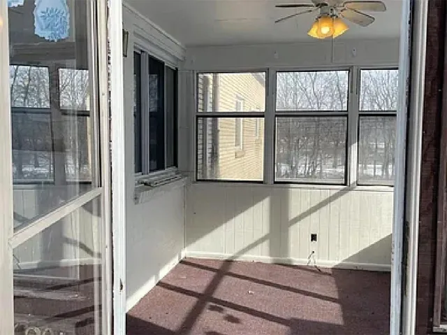 an empty room with wooden floor ceiling fan and windows