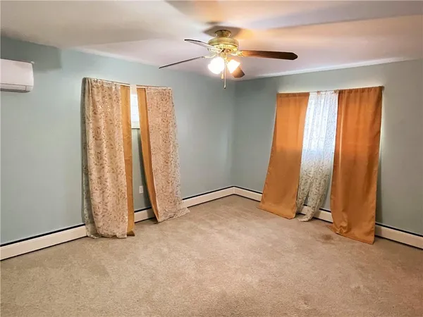an empty room with chandelier fan and windows