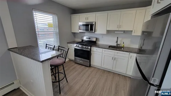 a kitchen with stainless steel appliances granite countertop a stove a sink dishwasher a microwave oven and a refrigerator with wooden cabinets