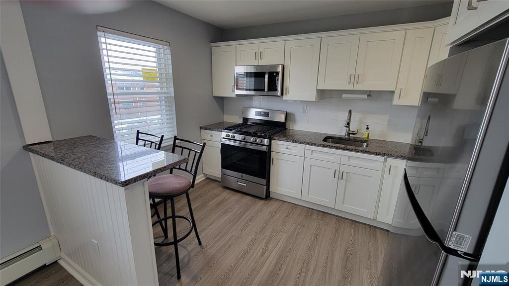 a kitchen with stainless steel appliances granite countertop a stove a sink dishwasher a microwave oven and a refrigerator with wooden cabinets