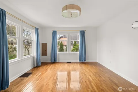 a view of an empty room with a window and wooden floor