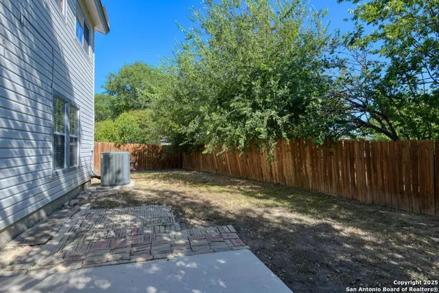 a view of a backyard with large trees and wooden fence