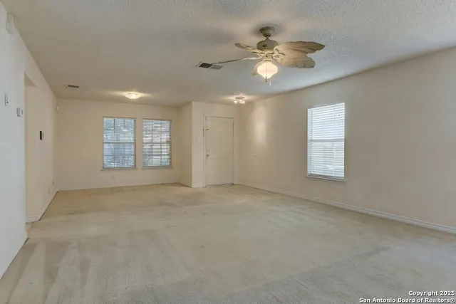 an empty room with windows and fan