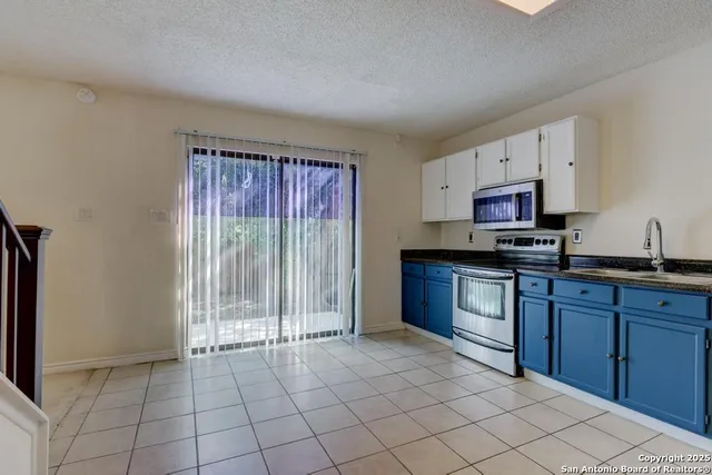 a kitchen with granite countertop a stove a sink and a microwave