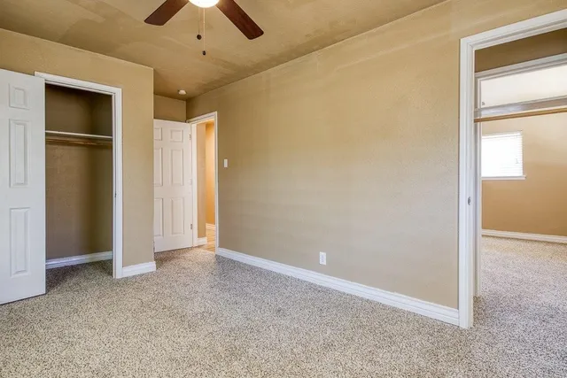 an empty room with closet and a chandelier fan