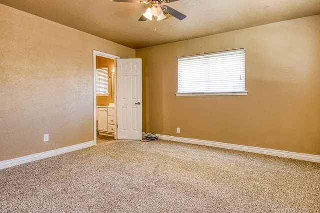 an empty room with a window and a ceiling fan