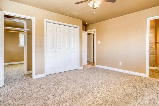 an empty room with closet and a chandelier fan