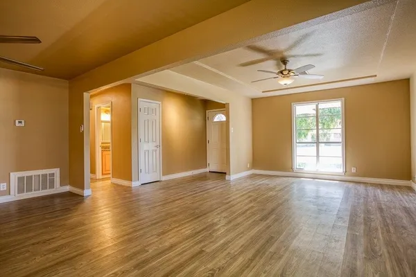 a view of an empty room with window and wooden floor