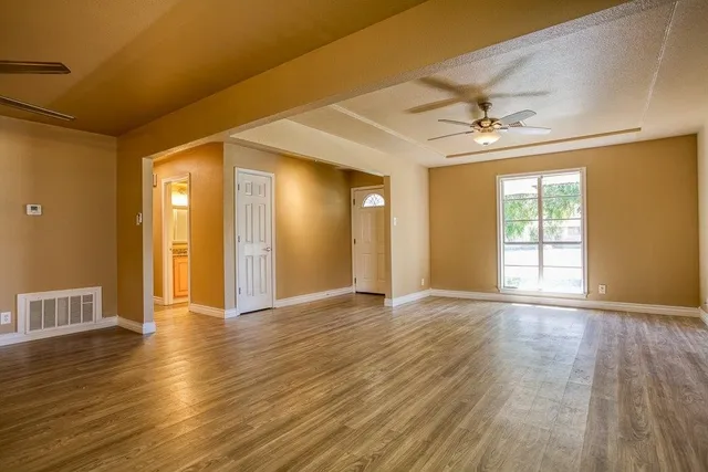 a view of an empty room with window and wooden floor