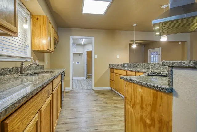 a large bathroom with a granite countertop sink and a wooden floor