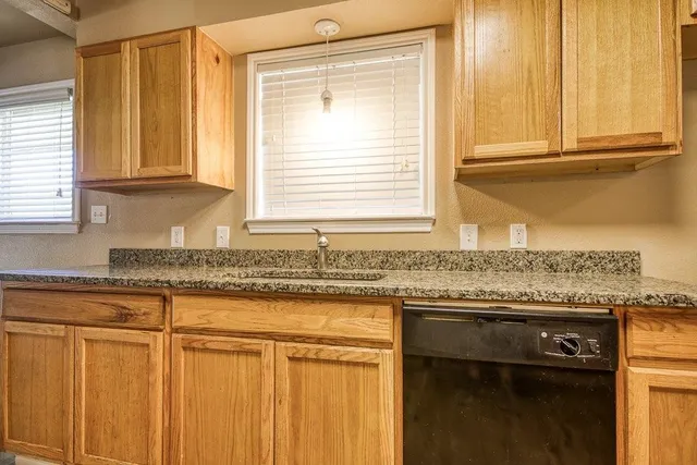a kitchen with granite countertop cabinets sink and window
