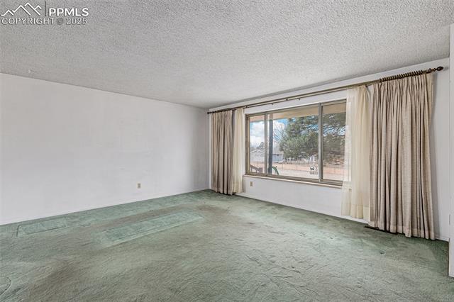 1653 Cragin Road Colorado Springs, CO 80920 - Photo 4 of 27 Empty room with a textured ceiling and carpet floors