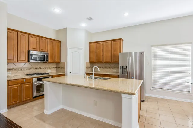 a kitchen with stainless steel appliances granite countertop a stove a sink and a microwave