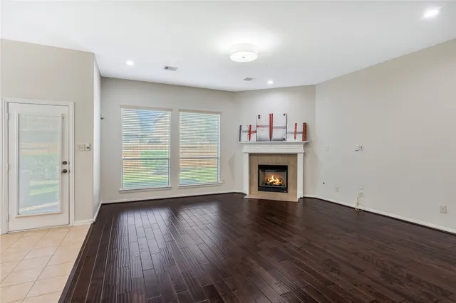 an empty room with wooden floor fireplace and windows