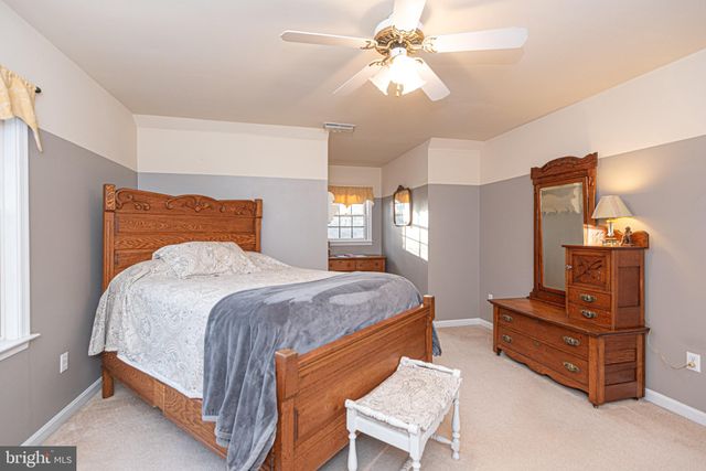 a view of a white house next to a yard with large trees