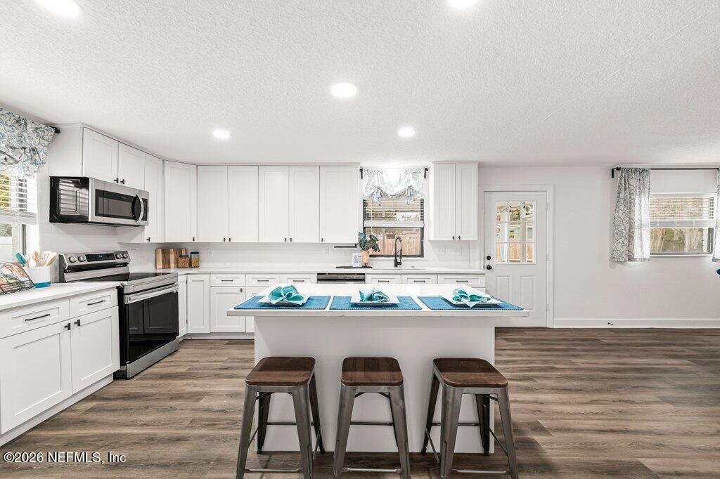 6731 Sans Souci Road Jacksonville, FL 32216 - Photo 11 of 27 a kitchen with stainless steel appliances kitchen island granite countertop a stove a sink a refrigerator and white cabinets with wooden floor