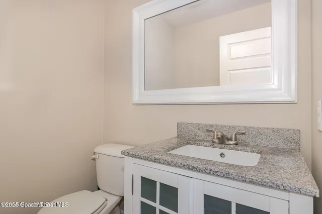 a bathroom with a granite countertop sink and a toilet