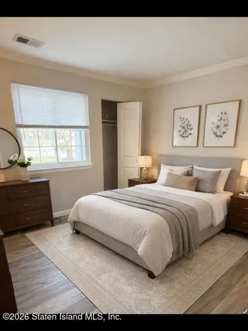 a bedroom with a bed a dresser and next to a window