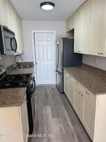 a kitchen with granite countertop a sink stove and refrigerator