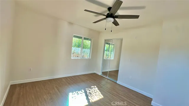 an empty room with wooden floor fan and windows