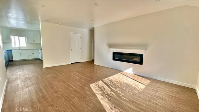 a view of empty room with wooden floor and fireplace
