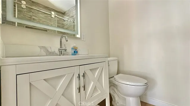 a bathroom with a toilet sink a mirror and vanity
