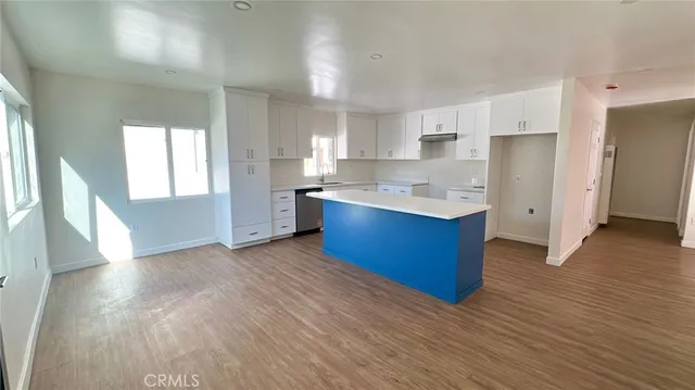 a kitchen with stainless steel appliances granite countertop a refrigerator a sink dishwasher a stove and white countertops with wooden floor