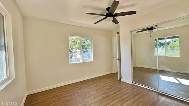 a view of empty room with wooden floor and fan