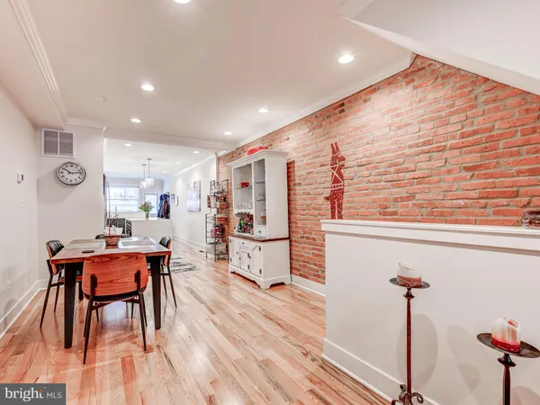 a kitchen with stainless steel appliances kitchen island granite countertop a refrigerator a stove a dining table and chairs with wooden floors