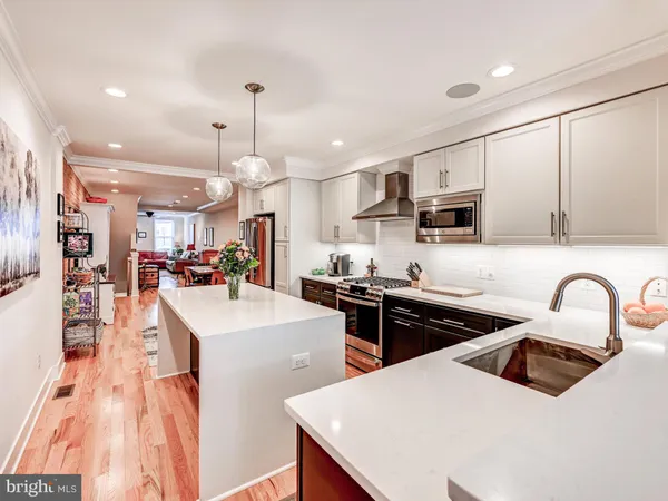 a kitchen with stainless steel appliances a sink a stove a refrigerator cabinets and chairs