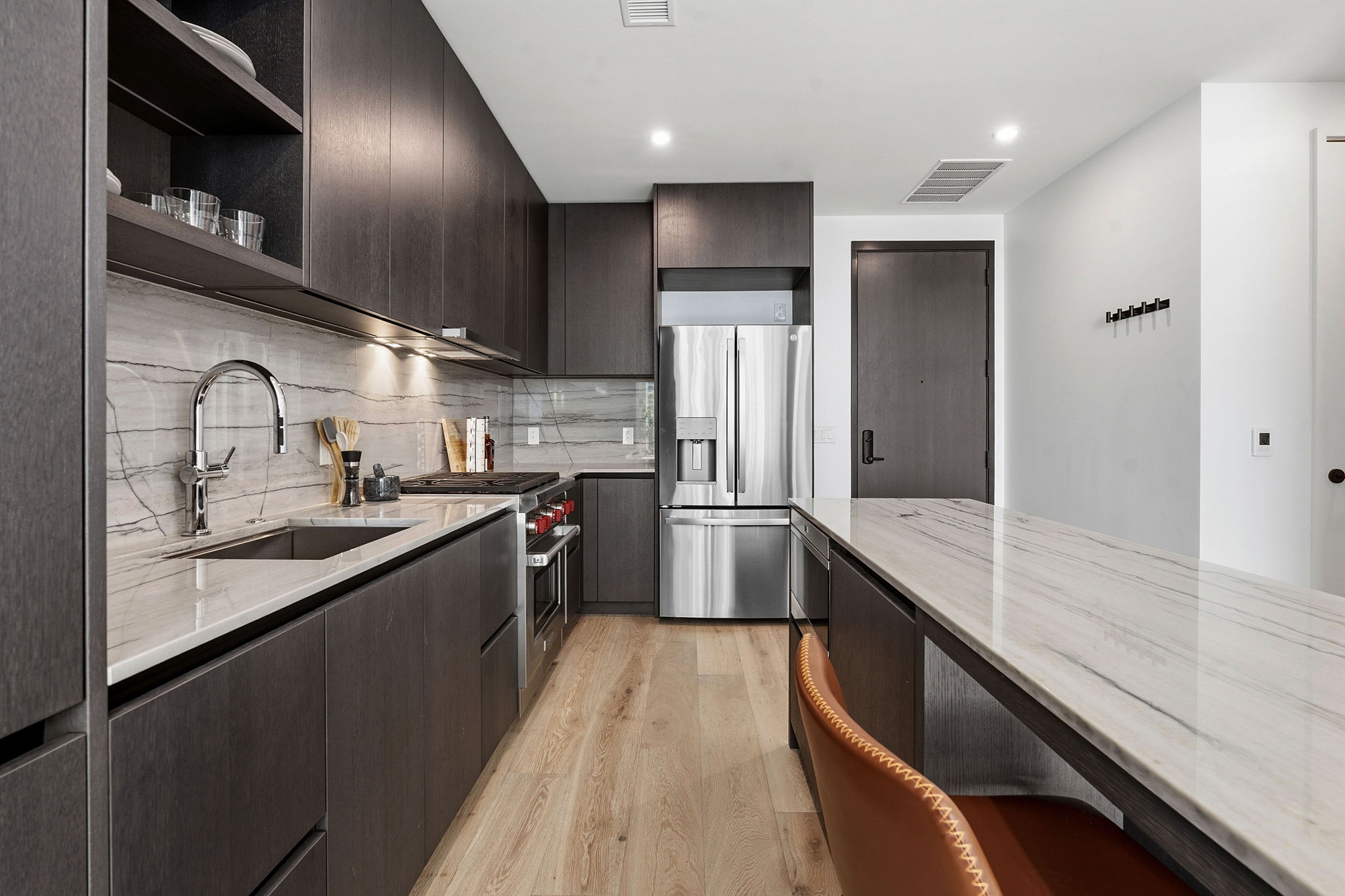 610 Davis Street, Unit 3004 Austin, TX 78701 - Photo 11 of 40 Kitchen with light stone counters, dark wood finish cabinets, modern cabinets, light wood-type flooring, and stainless steel appliances