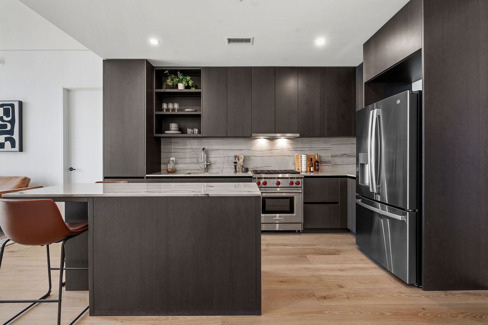 610 Davis Street, Unit 3004 Austin, TX 78701 - Photo 7 of 40 Kitchen featuring dark wood finish cabinets, open shelves, stainless steel appliances, modern cabinets, and light stone counters