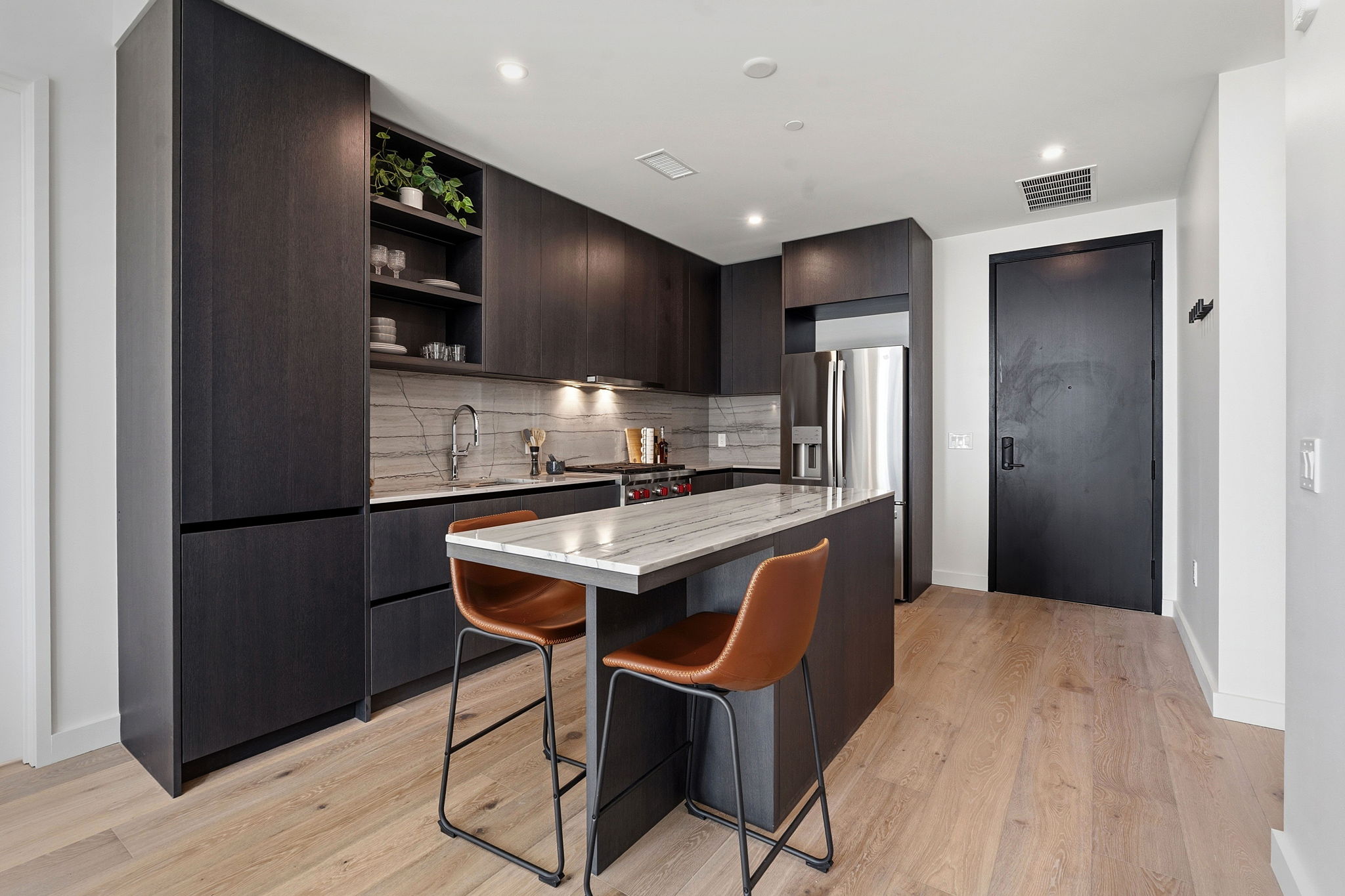 610 Davis Street, Unit 3004 Austin, TX 78701 - Photo 8 of 40 Kitchen featuring modern cabinets, dark wood finish cabinetry, a center island, a kitchen bar, and light wood finished floors