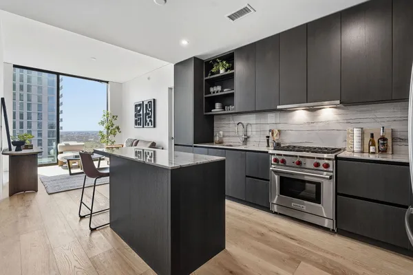 a dining room with stainless steel appliances kitchen island granite countertop a dining table chairs and a refrigerator