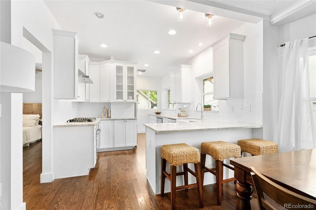 a kitchen with white cabinets and chairs