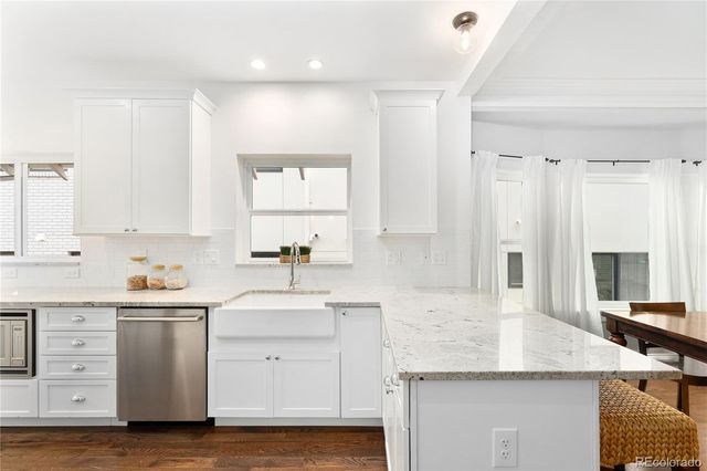 a kitchen with a sink dishwasher a stove and white cabinets with wooden floor