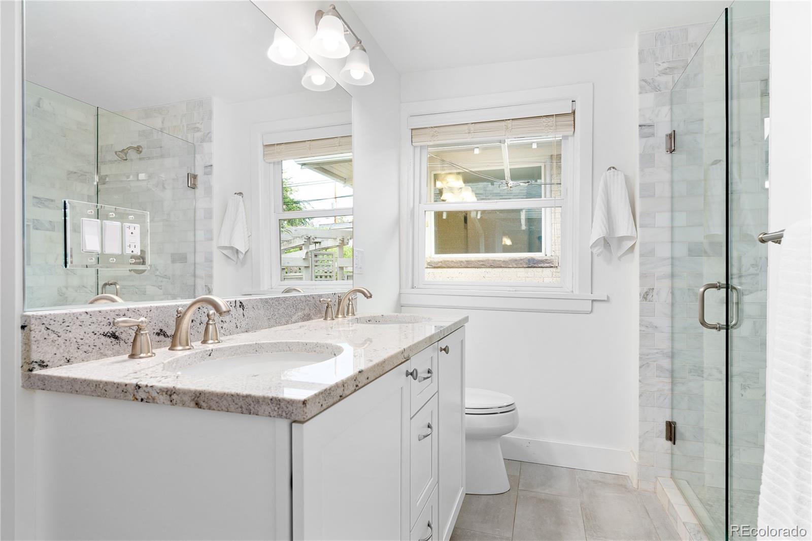 486 South Corona Street Denver, CO 80209 - Photo 26 of 46 a bathroom with a granite countertop sink a large mirror a toilet and a shower