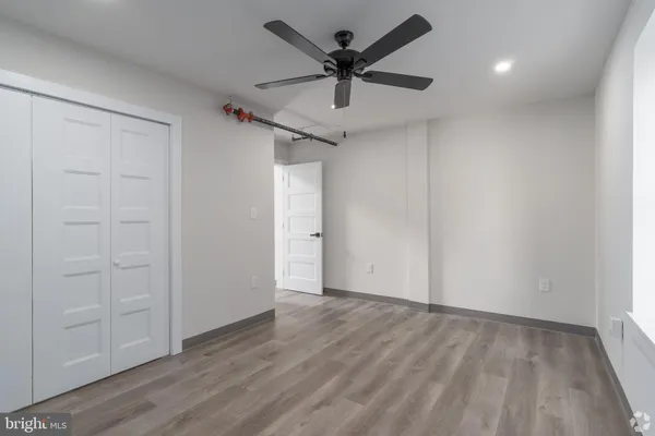 an empty room with wooden floor and ceiling fan